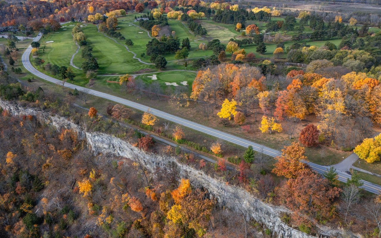 Illustrative woodland parkland golf image — aerial view of an autumn golf course in a wooded valley