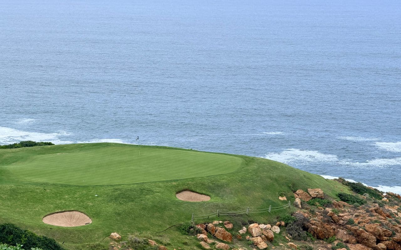 Illustrative coastal golf image — seaside links course with bunkers and ocean views